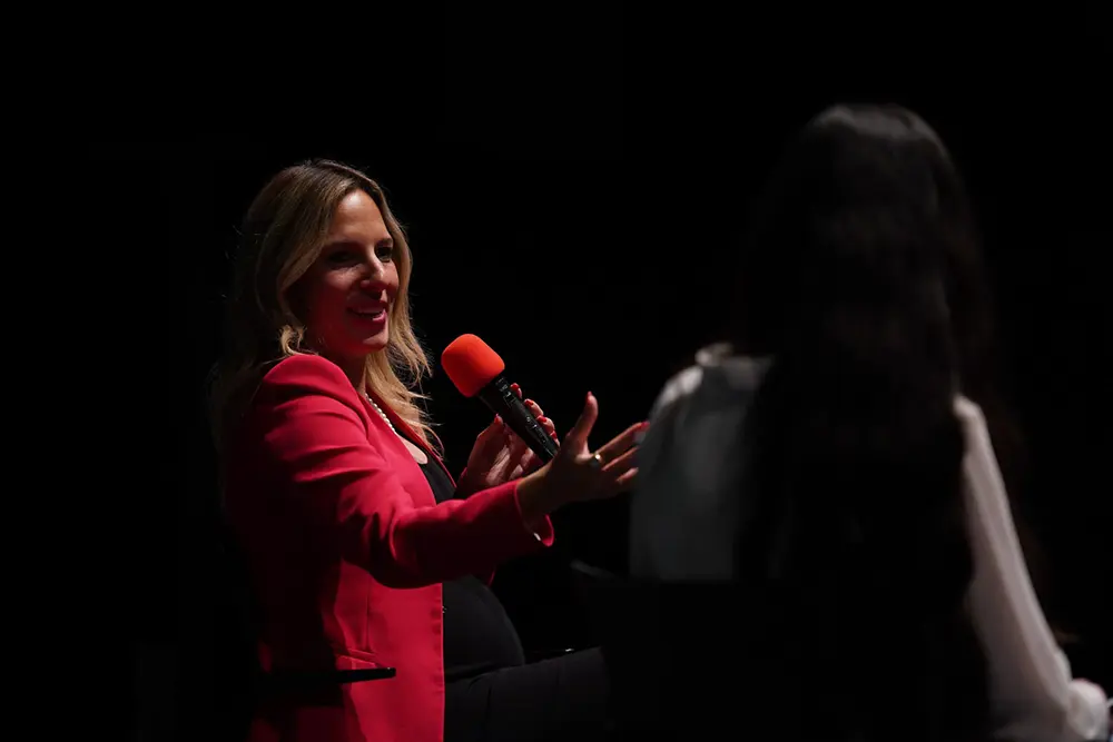 Speakerin Deniz Kayadelen im roten Blazer in einem Interviewformat